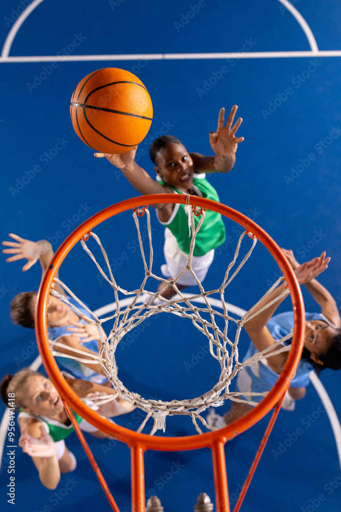 Wall mural Playing basketball, girl in green jersey jumping to score basket