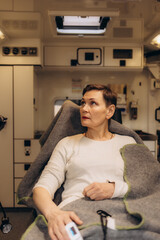 An injured older woman sits in an ambulance