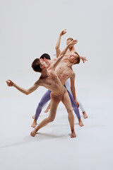 Fototapeta premium Group of dancers intertwines in motion, creating art with every step and stretch, showcasing their training against white studio background. Concept of music, dance, modern and classical art, movement