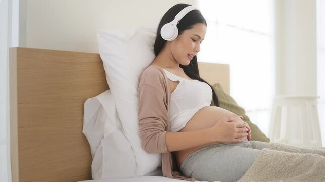 Happy pregnant woman with headphones listening to music