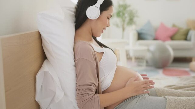 Happy pregnant woman with headphones listening to music