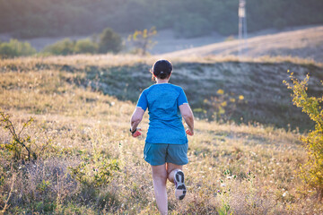 Woman running free on the hill on golden sunset.