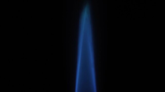 Blue flame of gas burner close-up on black background. Real time. Side view.