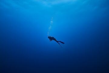Naklejka premium A diver floating in the middle of a blank blue expanse.