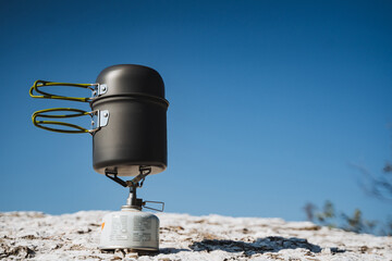 A pot is currently sitting on top of a propane burner on a snowy hill