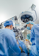 Surgeons performing complex procedure in an operating room. Surgeons wearing scrubs and masks...