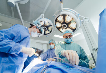 Surgical team performing an operation in a modern operating room. A surgical team consisting of doctors is focused on performing an operation in a high-tech operating room