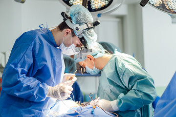Surgeons perform a complex operation in a modern operating room. Two surgeons focus intently as...