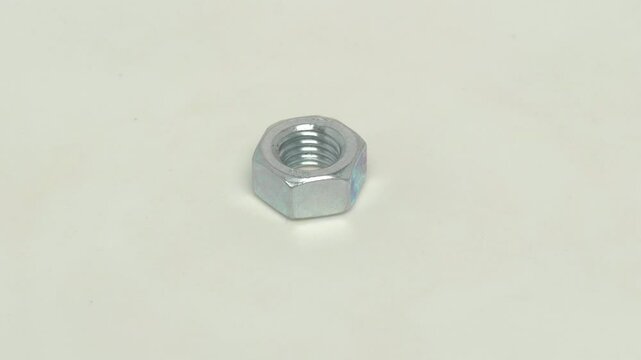 A Shiny Metal Nut strategically placed on a White Surface for enhanced visibility and effect