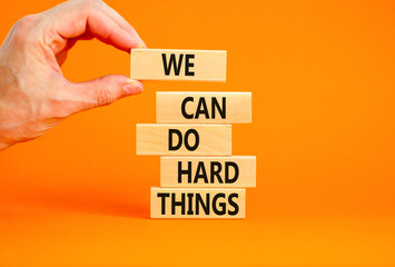 We can do hard things symbol. Concept words We can do hard things on wooden blocks. Beautiful orange table orange background. Businessman hand. Business, we can do hard things concept. Copy space.