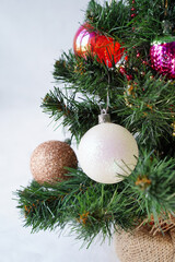 Decorated Christmas tree, template for greeting card. Green plastic Xmas tree with glittery balls and beads against white background. Vertical photo, copy space on the left. Background for New Year.