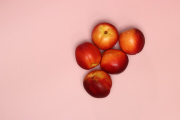 Ripe nectarines on a pink background with copy space. Flat lay, top view of fresh fruit on a table. Healthy eating concept. 