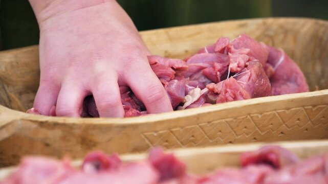 Closeup of mixing raw meat by hands in a wooden bowls. Craft culture of the Baltics. Historical reenactment. Rumsiskes, Lithuania- 07 05 2024. 