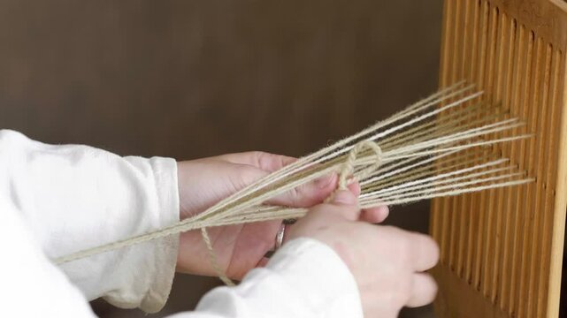 A woman weaves a ribbon using an ancient technique. Craft culture of the Baltics. Historical reenactment. Rumsiskes, Lithuania- 07 05 2024. 