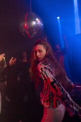 Portrait of a pretty young woman showing dance movements in the night club