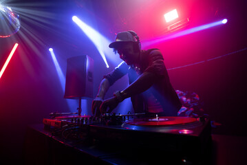 Top view of a DJ works in the club on the equipment, dancing and shaking his body