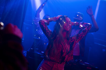 Focused DJ Mixing Music in Vibrant Nightclub and People Dancing Happily in Front of Turntable