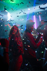 Vertical image of a crowd during colorful party in different clothes having fun and dancing at a...