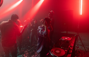 Crowded people dancing at party night club event deejay mixing music neon illuminated dance floor