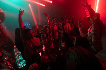 Female beautiful DJ performing on live stage, mixing music at night club disco party while crowded...