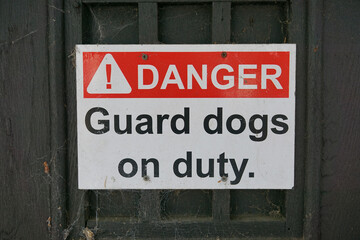 Guard dogs on duty warning sign on boundary fence. Danger notice of guard dogs on patrol 