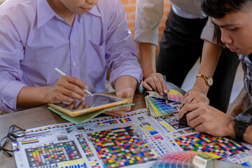 Team graphic designer checking print quality of media graphics proof print and color guides in...