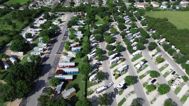 Flyover row of colorful cottage mobile home retreat vacation rentals, full hookup RV site in New Braunfels, concrete pads with electric service, suburban residential neighborhood San Antonio, TX