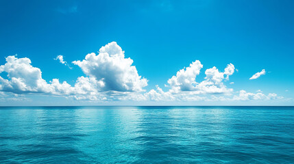 Obraz premium A clear blue sky meeting a turquoise sea, with a few white fluffy clouds floating above a tranquil, wide ocean expanse