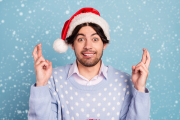 Photo of positive cheerful young man hold fingers crossed expect present isolated on blue color background