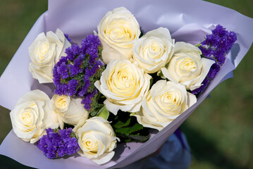 Bouquet of white roses with the addition of purple Limonium sinuatum flowers