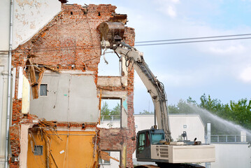 Excavator demolishes building wall, construction vehicle on ruins and debris, destructive power of...