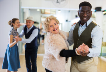 Man and senior woman dancing waltz in studio
