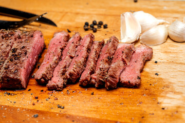 A piece of picanha meat is cut and sitting on a wooden cutting board with a fork and knife