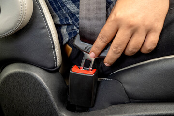A person is buckling their seatbelt in a car