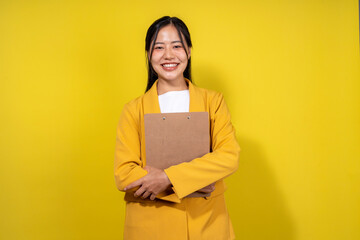 Fototapeta premium A woman in a yellow jacket is holding a brown book