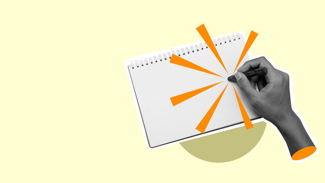 A hand is writing on a notebook with a bright orange tip