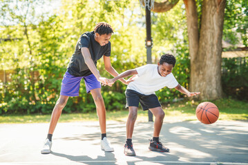 Fototapeta premium portrait of brother playing with a basketball in park