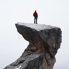 Obraz premium A lone hiker standing on a rocky outcrop overlooking a misty valley
