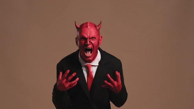 Red devil businessman getting angry on solid background