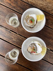 Two glasses of champagne and two oysters on a wooden table