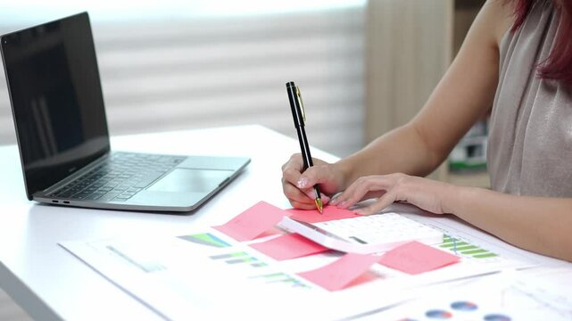 Businesswoman writing on sticky notes while working at office