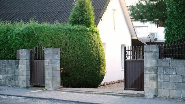 Closing of automatic entrance gate of brown color made of metal. Block fence. Entrance group for cars in the private house. Distance control. Smart home system