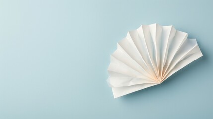 Elegant fan-shaped paper sculpture, delicate pleats arranged aesthetically, set against a soft blue backdrop, showcasing minimalist artistry and creative design.
