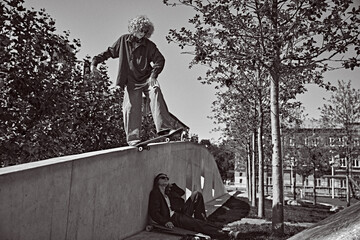 One stylish guy in motion. on skateboard riding on concrete pavement, while other boy resting on...