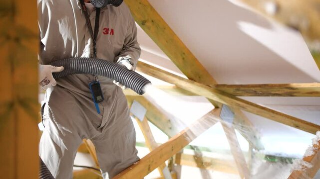House attic insulation - construction worker installing cellulose on the roof