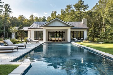 Elegant white pool house with outdoor dining and seating around a large rectangular pool, surrounded by green grass and trees in a New England backyard.