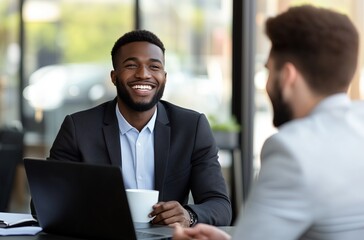 a smiling  businessman,  talking with a  client while working on a laptop during a meeting in the office.