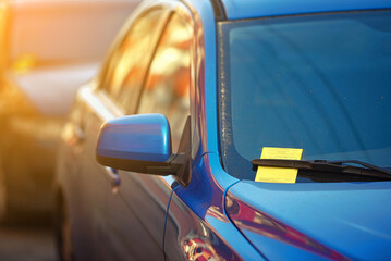 Parking ticket. Yellow payment notice for parking penalty secured under car's windshield wiper,...