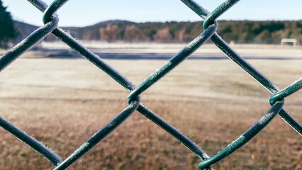 Frozen fence with frost next to a field on a very cold winter morning