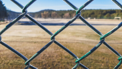 Frozen fence with frost next to a field on a very cold winter morning